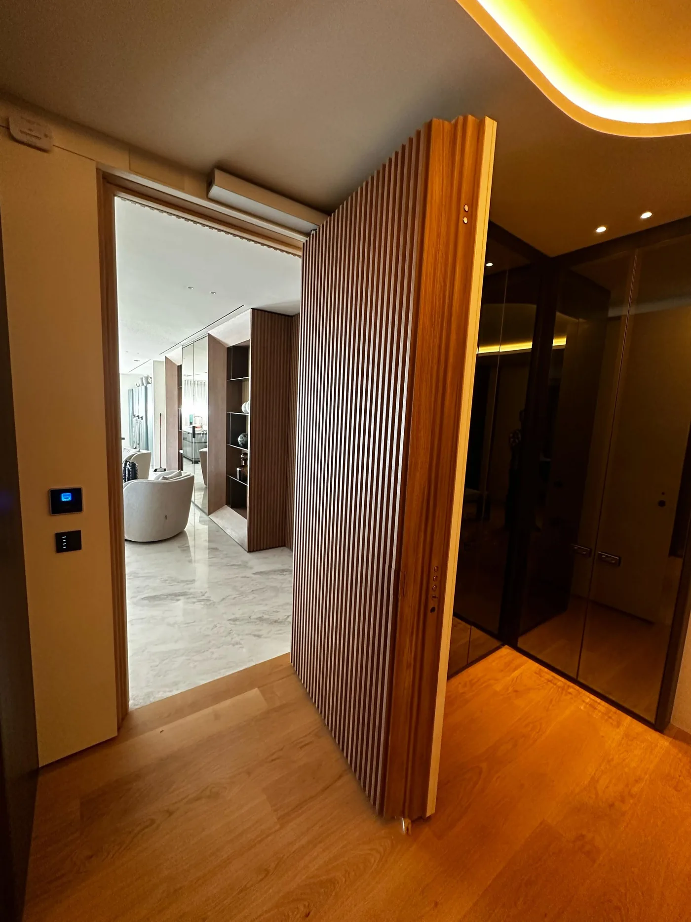The slatted wooden door open, with the access control recessed into its edge.